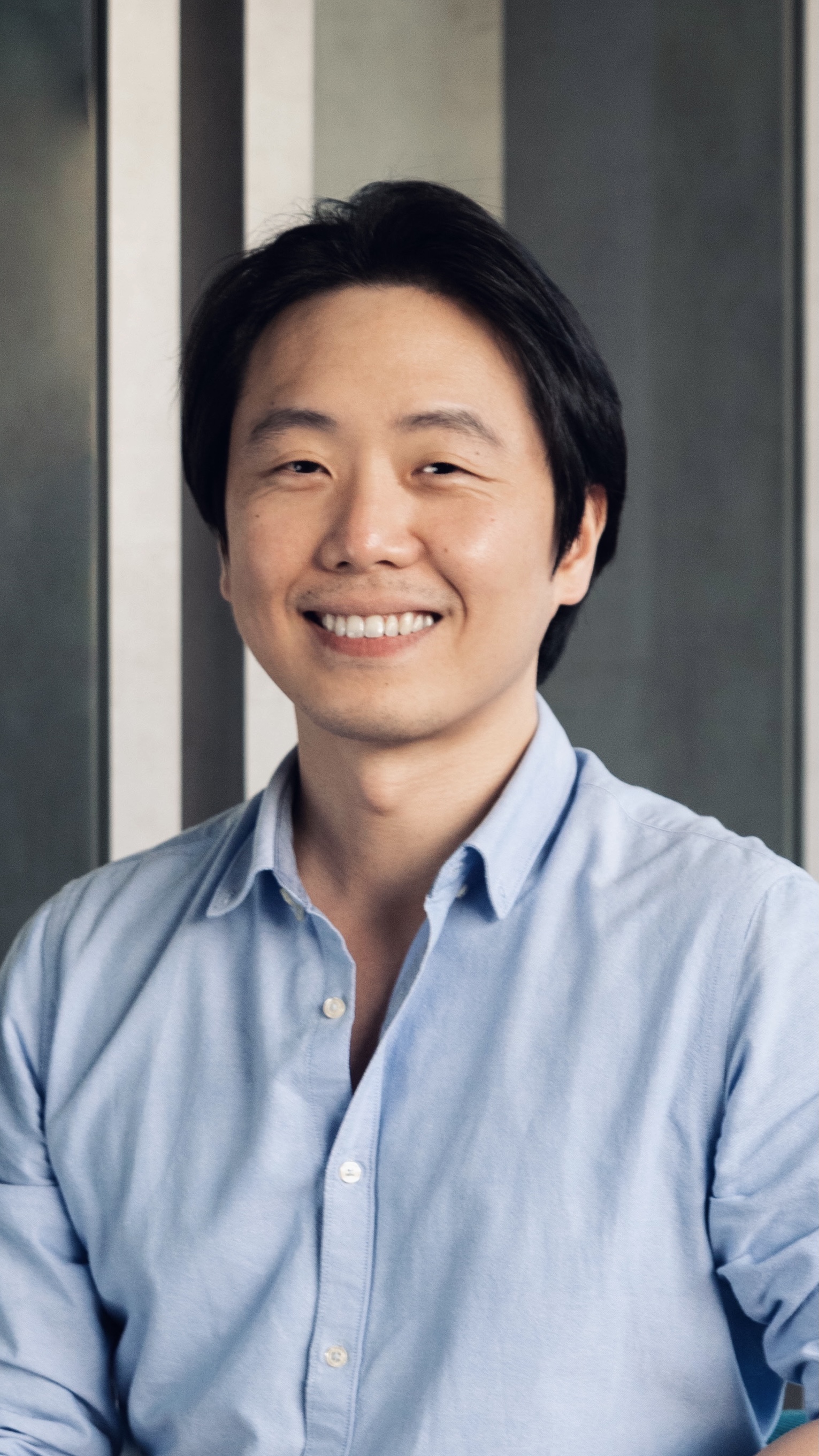 Derek Toh smiling in front of Hiredly signage.